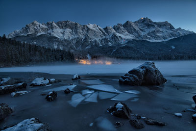 Scenic view of frozen lake by mountains against sky