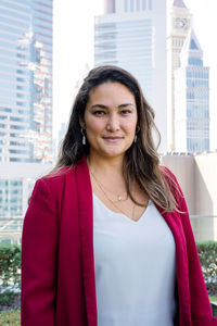 Portrait of smiling woman standing against buildings in city