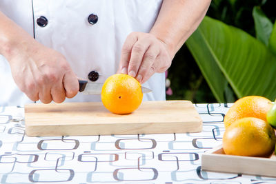 Cropped image of hand holding fruits on cutting board