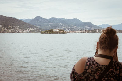 Rear view of young woman looking at sea against mountains