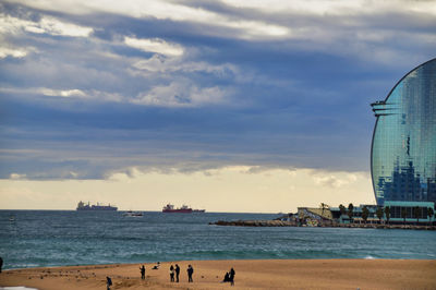 View of sea and people at beach against cloudy sky