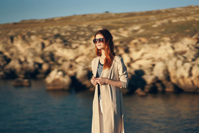 Rear view of young woman standing by water