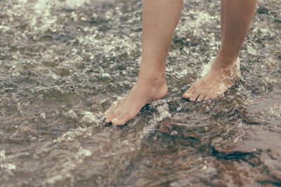 Low section of woman walking in stream