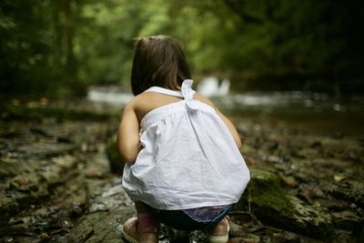 Rear view of girl crouching in forest
