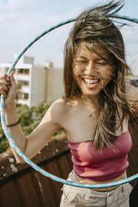 Happy young woman with hoola hoop enjoying on rooftop