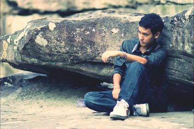 Side view of young man sitting outdoors