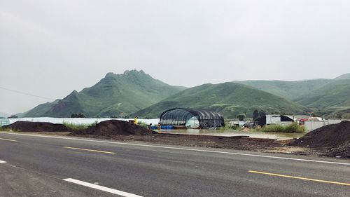 Road by mountains against clear sky