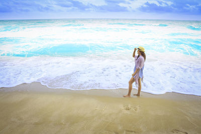 Woman standing on beach against sky