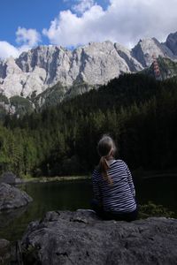 Rear view of woman sitting on rock