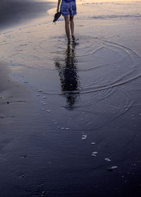 Low section of man standing on wet beach