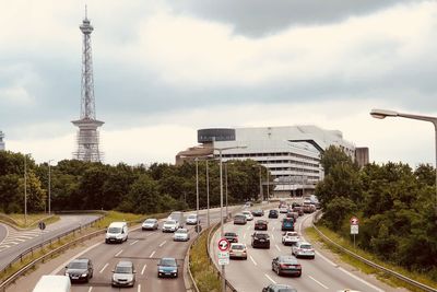 Traffic on road in city against cloudy sky