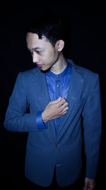 Young man standing against black background