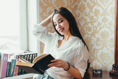 Young woman sitting on table at home