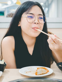 Asian woman holding chopsticks enjoying eating in shabu restaurant.