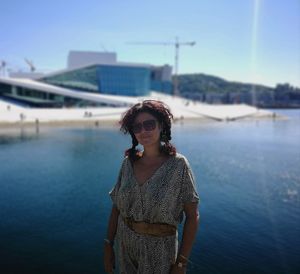 Portrait of woman wearing sunglasses standing against sea during sunny day