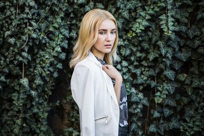 Portrait of young woman standing against plants