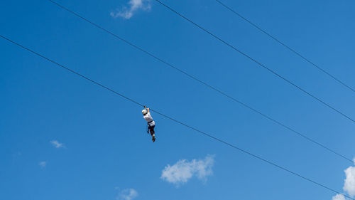 Low angle view of birds flying against blue sky