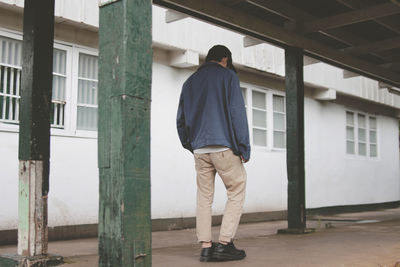 Rear view of man standing against building