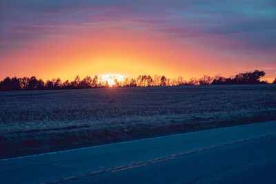 Scenic view of snowy field against sky during sunset