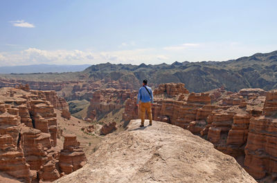 Man standing on a rock overlooking the magnificent screens of charyn canyon, kazakhstan
