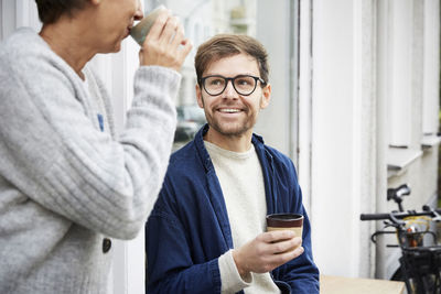 Smiling man with female colleague at entrance of art studio