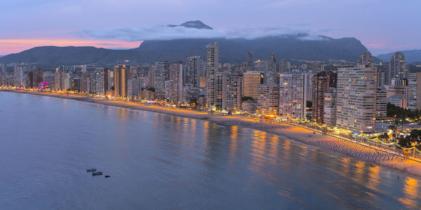 Scenic view of river by buildings against sky at dusk