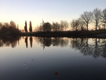 Reflection of silhouette trees in lake against sky