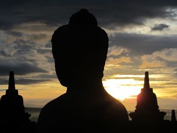 Rear view of silhouette man statue against sunset sky