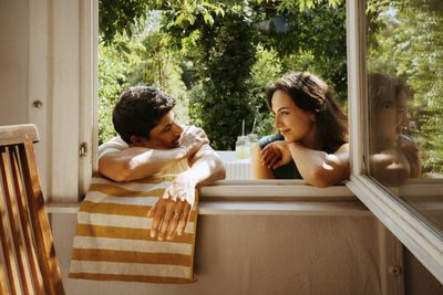 Romantic multiracial young couple leaning on window during dinner party