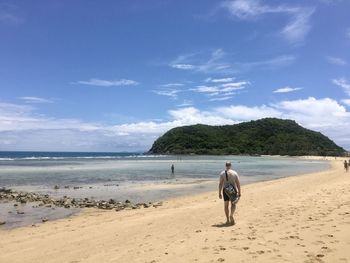 Rear view of man on beach against sky