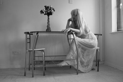 Portrait of seductive woman sitting on chair at home