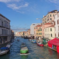 Boats moored in canal amidst buildings in city