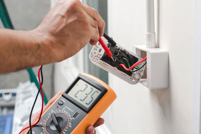Cropped hand of electrician repairing switch box