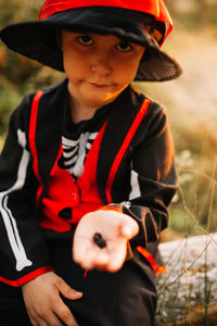 Portrait of boy wearing costume during halloween holding blackberries at forest