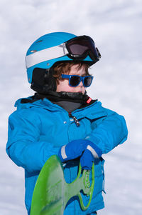 Cute boy with sled standing on snow covered land