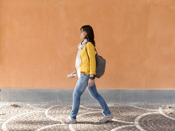 Side view of woman walking against wall