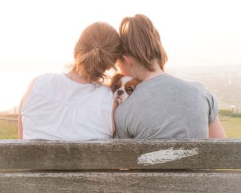 Rear view of friends embracing dog