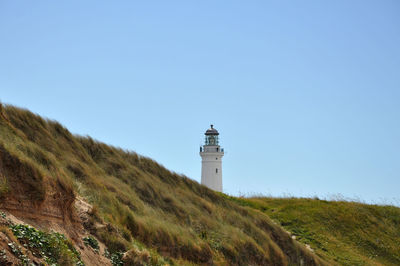 Lighthouse amidst buildings against sky