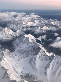 Aerial view of snowcapped mountains against sky during sunset