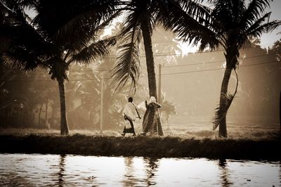 People walking on field by lake