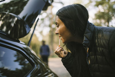 Side view of young woman looking through car windshield