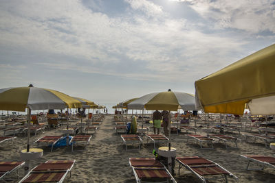 Chairs and parasols at beach against sky