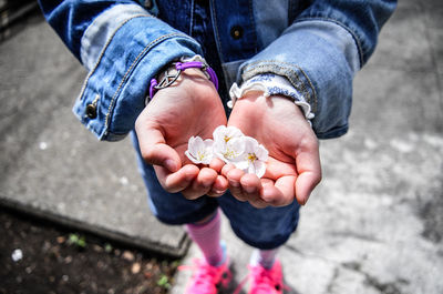 Low section of girl holding flowers while standing on street