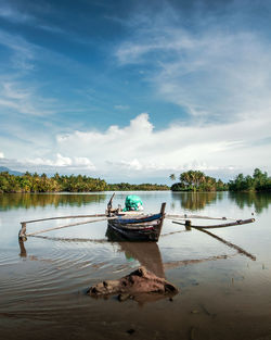 Boat moored in lake against sky
