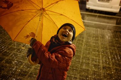 Full length of happy man holding umbrella in rain