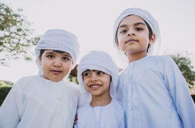 Smiling brothers wearing traditional clothing against clear sky