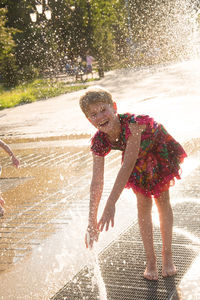 Full length of wet boy splashing water