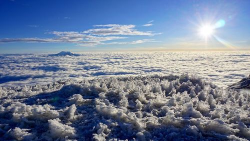 Scenic view of snow covered landscape against bright sun