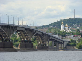 Arch bridge over river against sky in city