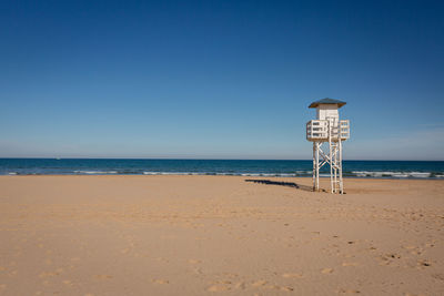 Lifeguard hut on beach against clear blue sky